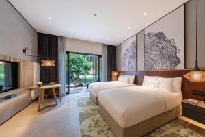 two beds in a hotel room with a tv and a bedroom at Melia Chongqing in Chongqing