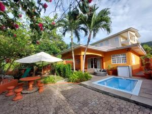 a house with a swimming pool and an umbrella at Beau Vallon Villa Self Catering With Pool in Beau Vallon