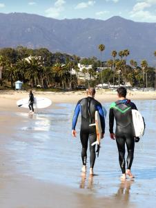 surfers walking along a beach with surfboards at Kimpton Canary Hotel, an IHG Hotel in Santa Barbara