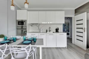 a kitchen with white cabinets and a table and chairs at Lion Apartments - Bosman I in Sopot