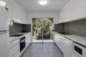 una cucina con mobili bianchi e una grande finestra di 14 The Islander Resort a Point Lookout Altre 2 foto