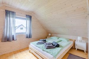 Ce lit se trouve dans une chambre en bois dotée d'une fenêtre. dans l'établissement Biale Domki Kopalino, à Kopalino