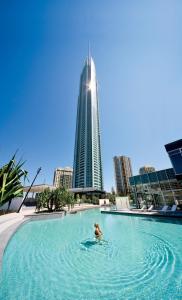 une personne dans une piscine avec un grand bâtiment dans l'établissement Q1 Resort & Spa - Official, à Gold Coast