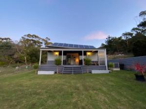 a small house with a solar roof on a yard at Bella Blue - Scamander River Stay in Scamander