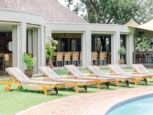 a group of lounge chairs next to a swimming pool at Lilayi Lodge in Lusaka