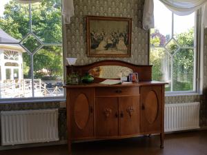 um quarto com um armário de madeira em frente às janelas em Villa Eira vandrarhem em Hjo