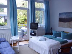 a bedroom with a bed and a tv and windows at Haus Alexandrine in Warnemünde