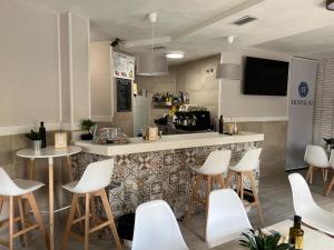 un restaurant avec des chaises blanches et un comptoir avec un bar dans l'établissement Hostal 82, à Olías del Rey