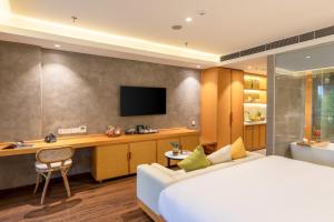 a hotel room with a bed and a desk and a television at Kua Casa Suite in Da Nang