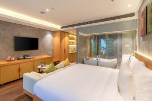 a bedroom with a large white bed and a tub at Kua Casa Suite in Da Nang
