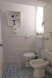 La salle de bains blanche est pourvue de toilettes et d'un lavabo. dans l'établissement CASA FIORE, à Corigliano dʼOtranto