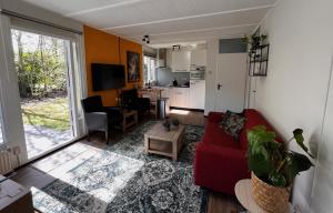 een woonkamer met een rode bank en een keuken bij Fijne plek met eigen bos 2000m2 en GRATIS linnen en handdoeken!! in Denekamp