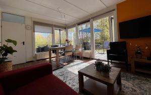 een woonkamer met een rode bank en een tafel bij Fijne plek met eigen bos 2000m2 en GRATIS linnen en handdoeken!! in Denekamp