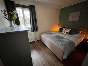 een slaapkamer met een bed en een vaas met bloemen bij Fijne plek met eigen bos 2000m2 en GRATIS linnen en handdoeken!! in Denekamp