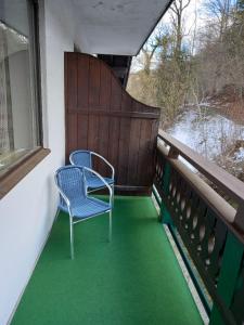 uma cadeira azul sentada numa varanda com alcatifa verde em Gasthof zum Pfandl em Bad Ischl