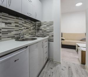 uma cozinha com um lavatório e um sofá num quarto em Elem apartmani em Tuzla