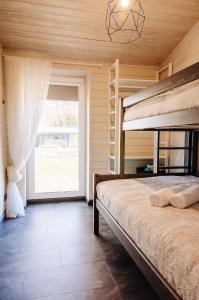 a bedroom with a bunk bed and a large window at Holiday Houses LILLE`S with sauna in Alūksne
