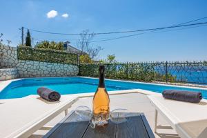 een fles wijn op een tafel naast een zwembad bij Sun Villa in Dramalj
