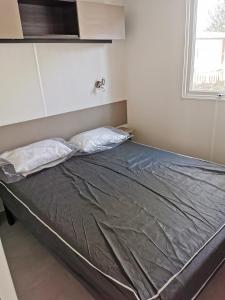 een bed in een kamer met 2 kussens bij MOBIL HOME SERENITE 2CH VALRAS PLAGE in Valras-Plage