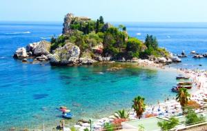 een strand met een stel mensen in het water bij LA VELA RECANATI in Giardini Naxos