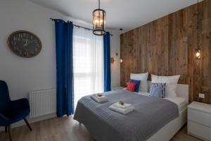 a bedroom with a bed with blue curtains and a clock at APARTAMENTY MIERZEJA -OSIEDLE BURSZTYNOWE, Jantar in Jantar