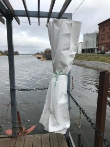 łódź przywiązana do przystani z białą torbą w obiekcie Houseboat on the water w mieście Lipawa