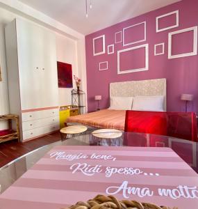sypialnia z fioletowymi ścianami, łóżkiem i stołem w obiekcie Bellini w Cagliari