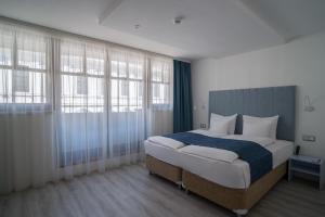 a bedroom with a large bed and windows at Hotel Civitas in Sopron
