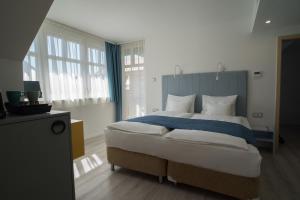 a bedroom with a large bed with blue and white pillows at Hotel Civitas in Sopron