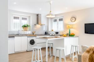 una cucina con armadi bianchi e un'isola cucina con sgabelli. di Plaza España, acogedor apartamento con patio a Siviglia