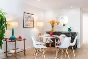 comedor con sillas blancas, mesa y espejo en Plaza España, acogedor apartamento con patio by OUTIN, en Sevilla
