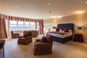 a bedroom with a bed and a couch and chairs at Inver Lodge in Lochinver