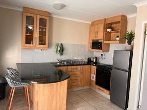 a kitchen with wooden cabinets and a black refrigerator at Stay @ 24 Malachite in Knysna