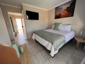 a bedroom with a bed and a flat screen tv at Stay @ 24 Malachite in Knysna