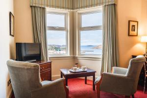 a hotel room with a television and two chairs and a table at Inver Lodge in Lochinver