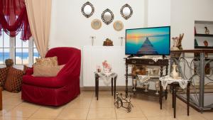 een woonkamer met een rode stoel en een tv bij Castel View Experience in Kissamos