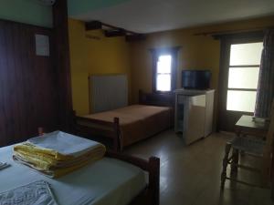 a hotel room with two beds and a television at Triple studio room in Mylopotamos Beach in Tsagarada