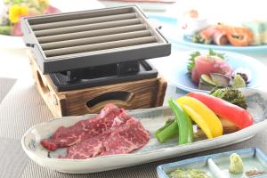 a grill with meat and fruits and vegetables on a table at Hotel Binario Saga Arashiyama in Kyoto