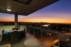 a balcony with a table and chairs and a sunset at Curtis Central Apartments in Gladstone
