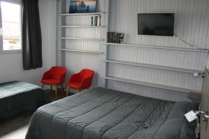 a bedroom with a bed and two red chairs at Hôtel Le Relais Dax in Dax