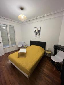 a bedroom with a yellow bed with a table on it at Un appartement authentique à deux pas de Paris . in Saint-Mandé