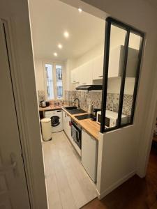 a kitchen with white cabinets and a stove top oven at Un appartement authentique à deux pas de Paris . in Saint-Mandé