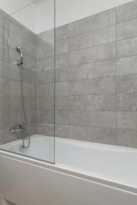 a shower with a glass door on a bath tub at Parizs Garden Apartments in Debrecen