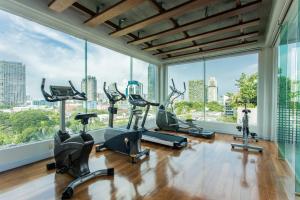 un gimnasio con máquinas cardiovasculares y ventanas grandes en D Varee Montara Thonglor 25, en Bangkok