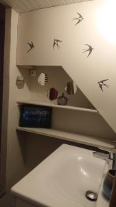 a bathroom with birds on the wall above a sink at Nuits au Grenier de Chartres in Chartres
