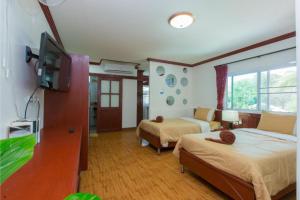 a bedroom with two beds and a flat screen tv at Patong Rai Rom Yen Resort SHA in Patong Beach