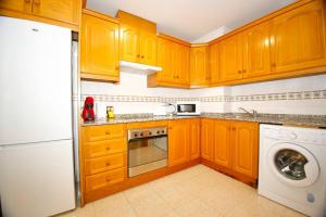 uma cozinha com armários de madeira e uma máquina de lavar roupa em Castaños apartment with AC em Alicante