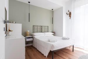a white bedroom with a bed and a table at LUVI - Pasubio in Milan