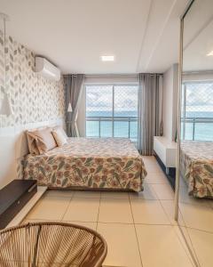 a hotel room with a bed and two chairs at Modern Beachfront Apartment w. Magnificent Seaview in Fortaleza
