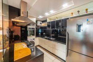 una cocina con nevera de acero inoxidable y armarios blancos en Modern Beachfront Apartment w. Magnificent Seaview, en Fortaleza